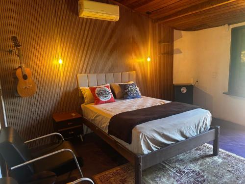 - une chambre avec un lit et une guitare sur le mur dans l'établissement Cervejaria Guest House, à Île de Boipeba