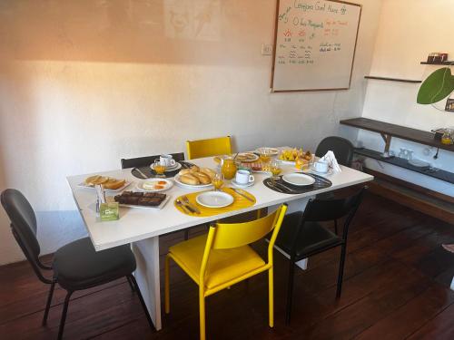 een witte tafel met gele stoelen en eten erop bij Cervejaria Guest House in Ilha de Boipeba
