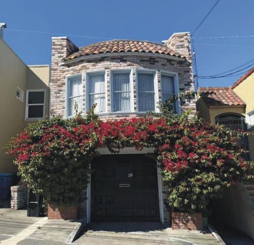 a house with a black garage with red flowers at Cozy 2BR, Totally Private With Parking, Convenient Public Transit in San Francisco