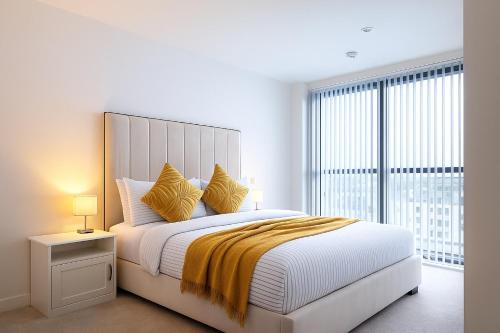 a white bedroom with a large bed with yellow pillows at Modern Duplex apartment City Centre Manchester in Manchester