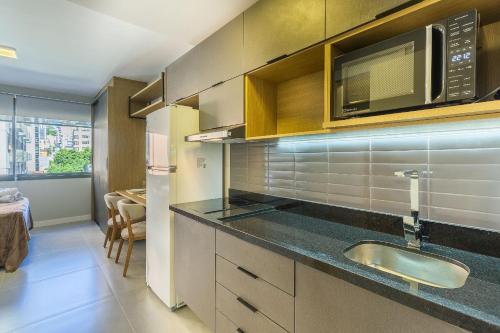 a kitchen with a sink and a microwave at Novíssimo - Skyline Parque Moinhos in Porto Alegre
