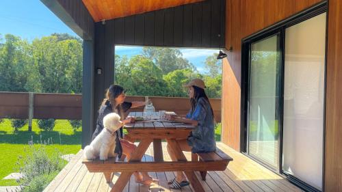 three women sitting at a picnic table with a dog at Casa Molino - Casa en Complejo Land Houses A Dos cuadras de Cruz del Sur, Chapadmalal - Hola Sur in Chapadmalal