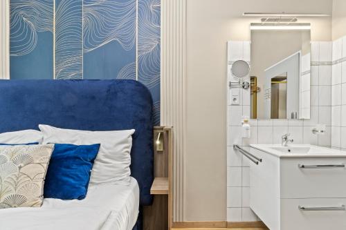 a bathroom with a bed with a blue headboard and a sink at Nestroyplatz Rooms I Self Check In in Vienna