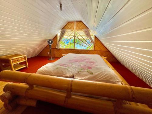 Bett in einem kleinen Zimmer mit Fenster in der Unterkunft Marū Beach House in Afareaitu