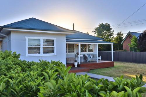 a white house with a deck and a fence at The Corner Cottage in Mudgee