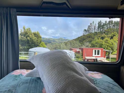 ein Schlafzimmerfenster mit Blick auf ein rotes Haus in der Unterkunft Simple Cabin, Kuaotunu - Peaceful, Affordable Stay in Kuaotunu