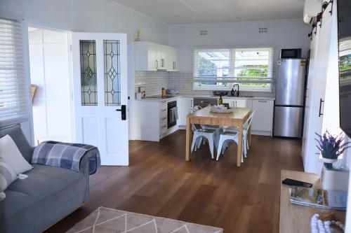 a kitchen and living room with a table and a couch at The Corner Cottage in Mudgee