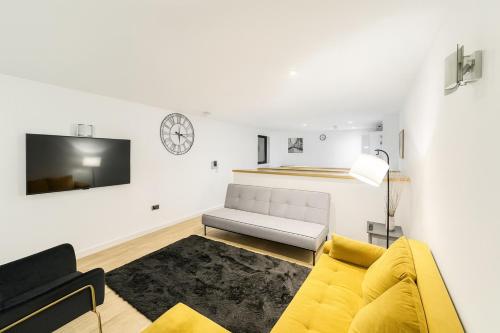 a living room with a yellow couch and a tv at Modern Duplex apartment City Centre Manchester in Manchester