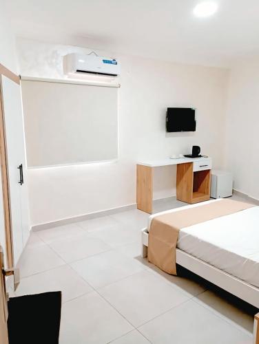 a white room with a bed and a tv at Hotel du Golfe de Guinée in Conakry