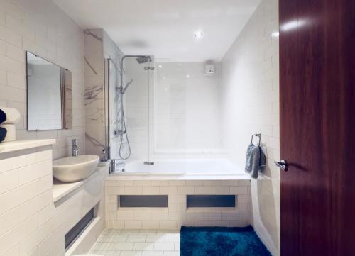 a bathroom with a tub and a sink and a mirror at Modern Duplex apartment City Centre Manchester in Manchester