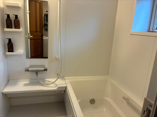 a white bathroom with a tub and a sink at 薪ストーブが体験できるログハウス #貸別荘 #一棟貸切 #グループ旅行や家族旅行におすすめ #札幌市内から好アクセス #満天の星空 #木の香り #BESS札幌 #cape in Sapporo