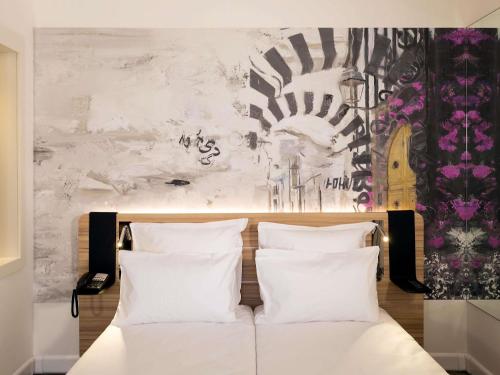 a bed with white pillows in front of a wall at Novotel Tunis Lac in Tunis