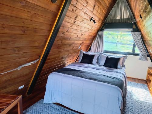 a bed in a room with a wooden wall at chalé okinawa in Gonçalves