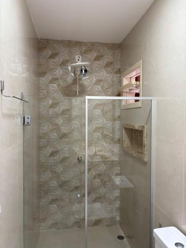 une douche avec une porte vitrée dans une salle de bain dans l'établissement Apartamento Centro Guriri 3 Quartos, à São Mateus