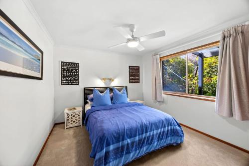 a bedroom with a bed with a blue comforter and a window at Boston Beach House - BYO Linen in Lorne