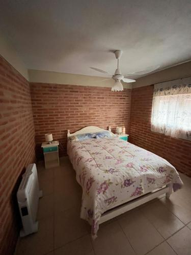 ein Schlafzimmer mit einem Bett und einer Ziegelwand in der Unterkunft Cabañas Don Lelio 2 in Mina Clavero