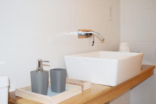 a white sink and two cups on a wooden counter at Valletta Mint Apartment 1 in Valletta