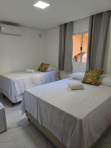 two beds in a room with a window at Hotel Pousada Velas ao Mar in Maceió