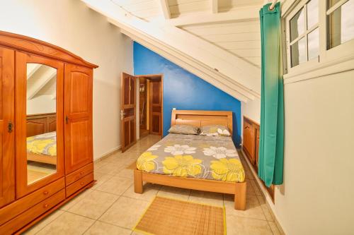 ein Schlafzimmer mit einem Bett und einer blauen Wand in der Unterkunft Le Flamboyant in Saint-Louis