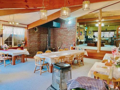a restaurant with tables and chairs and a brick wall at Guesthouse PAW in Nagano