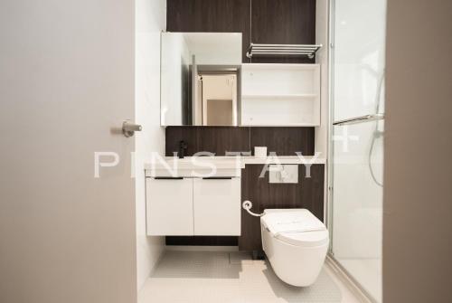 a white bathroom with a toilet and a mirror at Bay Suites by Pinstay Plus in Kota Kinabalu