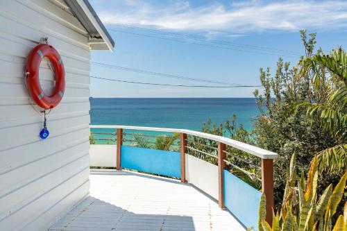 a house with a balcony with the ocean in the background at Surf Shack at Boat Beach in Seal Rocks