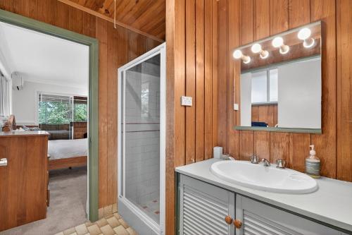 une salle de bain avec un lavabo, un miroir et une douche dans l'établissement Natures Haven Wentworth Falls with Sauna & Pool, à Wentworth Falls