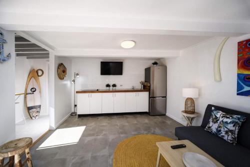 a living room with a couch and a kitchen at Surf Shack at Boat Beach in Seal Rocks