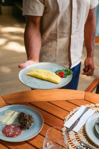 uma pessoa que segura um prato de comida numa mesa em Saluz Boutique Hotel em Jericoacoara