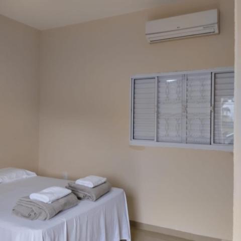a white room with a bed with towels on it at Chácara e Pousada Aeroporto in Andradina