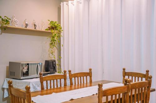 een eettafel met een magnetron en stoelen bij Apartamento 1 Quarto Canasvieiras in Florianópolis