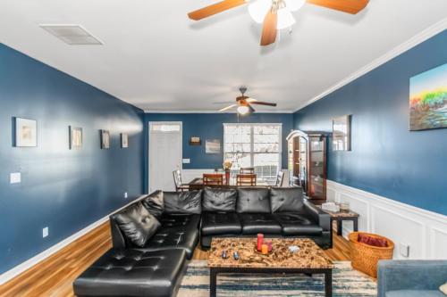 ein Wohnzimmer mit einem schwarzen Ledersofa und blauen Wänden in der Unterkunft 4 - Bed home with Cali King Bed, 12 mins to DTWN in Atlanta