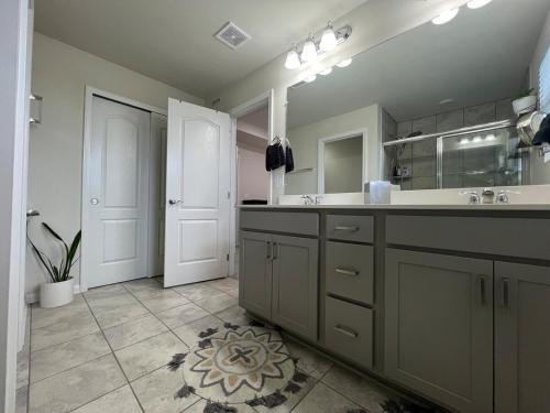 une salle de bain avec un lavabo et un grand miroir dans l'établissement Kensington Kickback QUICK Access to Ann Arbor, 