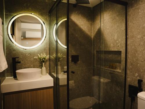 um banheiro com chuveiro, pia e espelho em Apê Itaim Bibi - Soft Opening em São Paulo