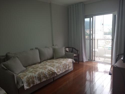 ein Sofa im Wohnzimmer mit Glasschiebetür in der Unterkunft Apartamento no centro de São Lourenço in São Lourenço