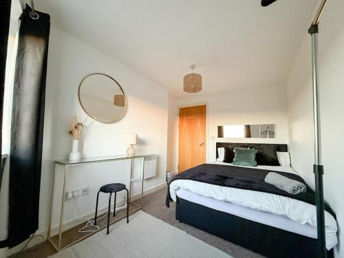 a bedroom with a bed with a mirror and a stool at Stylish 2-Bed Apartment in Central Bolton in Bolton