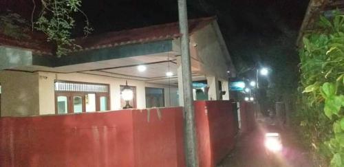 Una valla roja delante de un edificio por la noche. en Indivilla, en Kalutara