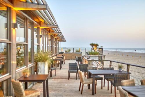 een restaurant op het strand met tafels en stoelen bij Delft Apartment CPI in Tanjungbunga