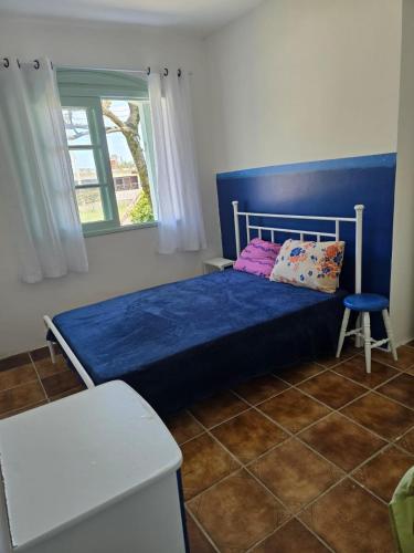 a bedroom with a blue bed and a window at Vida Mansa Apartamentos in Capão Novo