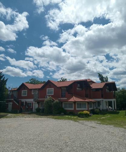 a large red house with a gravel driveway at Posada Los Alamos in Merlo