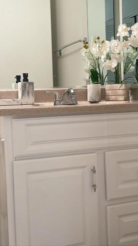 a bathroom counter with a sink with a vase of flowers at New Ocean View Condominium Free parking in Honolulu