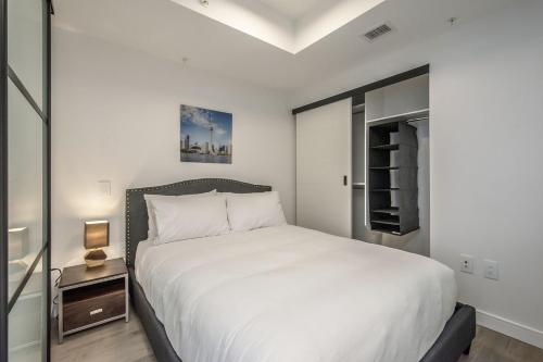 ein Schlafzimmer mit einem großen weißen Bett und einem Nachttisch in der Unterkunft Cozy 2BR Apt with Gym and Cinema near Pier 21 in Halifax