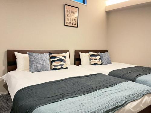 two beds sitting next to each other in a bedroom at Liaison Court Nishikujo Universal Bay 2 in Osaka