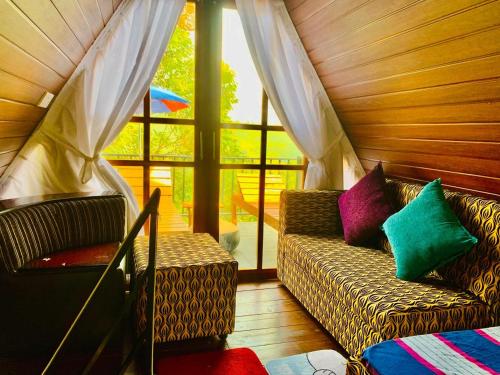 un salon avec un canapé et une fenêtre dans l'établissement Namunuku mount heaven cabana & resort,passara, à Passara