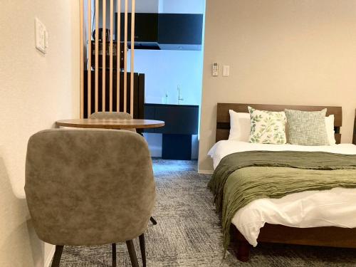 a bedroom with a bed and a table and a chair at Liaison Court Nishikujo Universal Bay 2 in Osaka