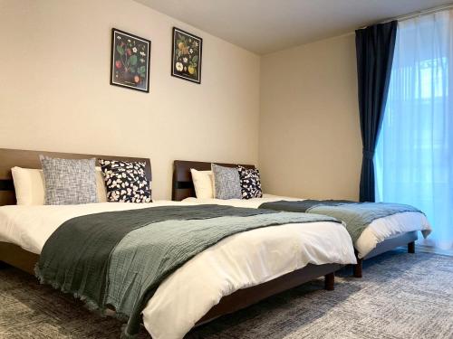 a bedroom with two beds and a window at Liaison Court Nishikujo Universal Bay 2 in Osaka