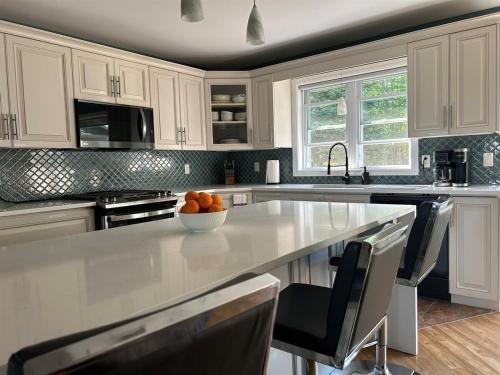 a kitchen with white cabinets and a bowl of oranges on a counter at Rutledge Lake Retreat in Bancroft