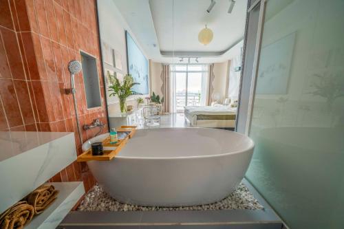 a bathroom with a large white tub and a shower at Aimee House Vũ Miên in Hanoi