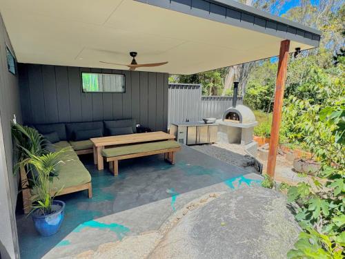a patio with a bench and a table and a grill at Coastal Garden Escape - Spa - Pizza oven in Moruya Heads