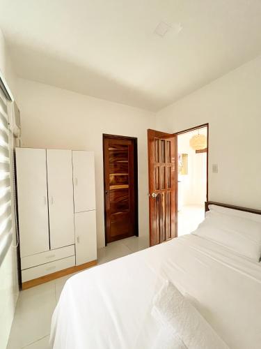 - une chambre blanche avec un lit blanc et une porte en bois dans l'établissement Zande Point Apartments, à General Luna